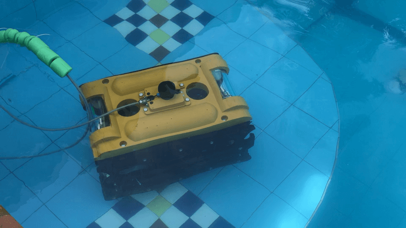The yellow autonomous underwater vehicle submerged in a tiled swimming pool during development