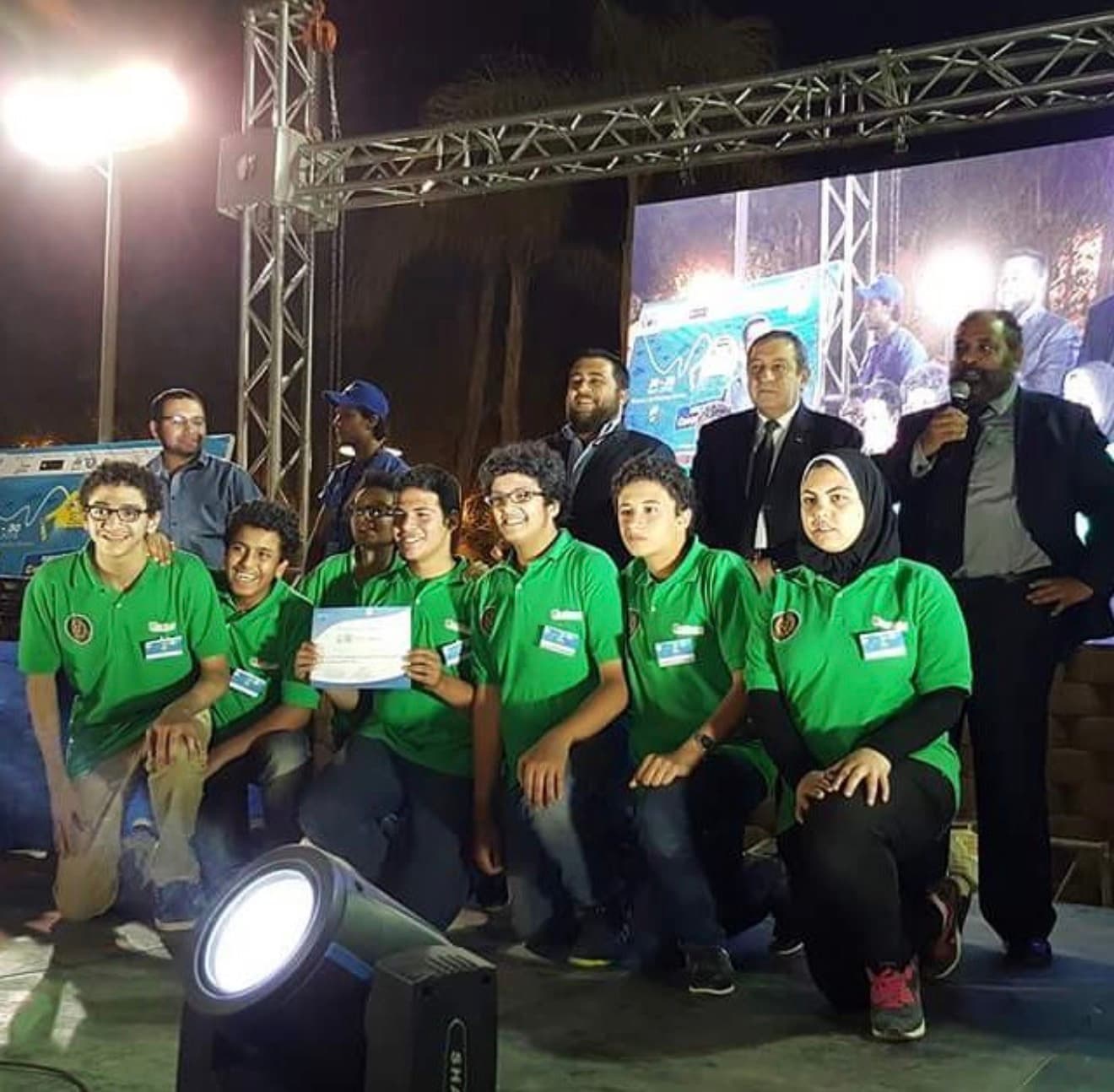Our team in green shirts at an underwater robotics awards ceremony, holding a certificate and trophy