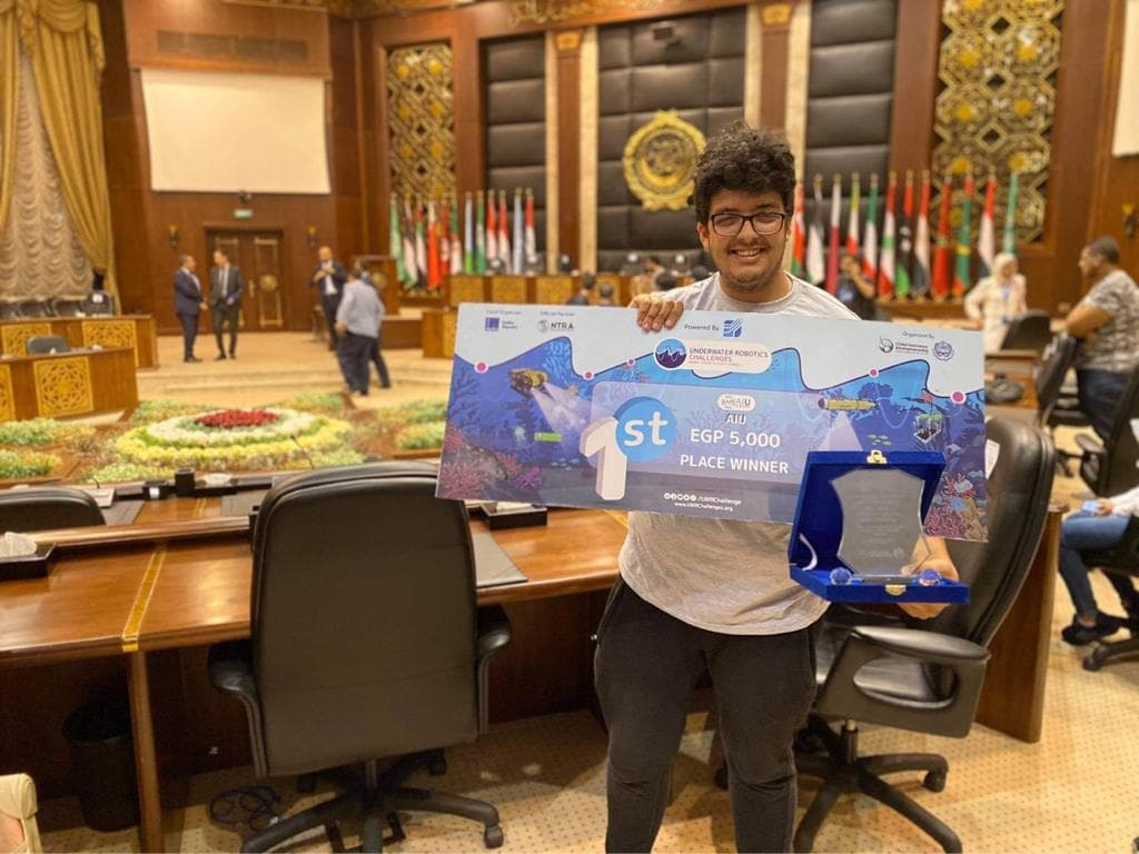Holding a first-place Underwater Robotics Challenges award and a plaque